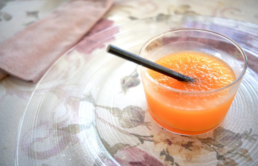 Agua de Valencia cocktail with a straw on a floral tablecloth.

